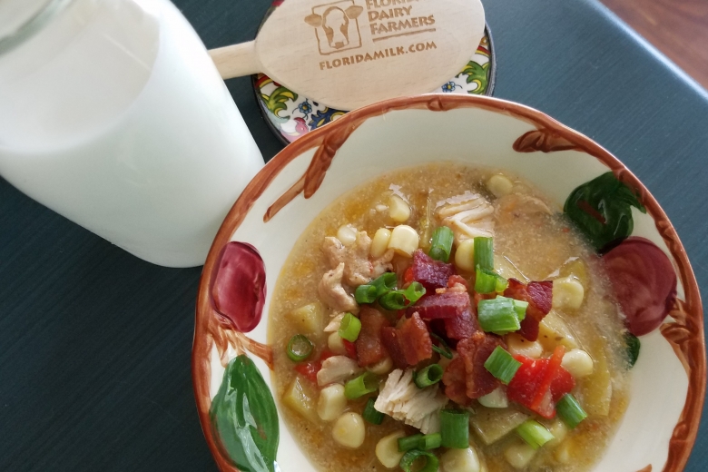 chicken and sweet corn chowder in bowl next to glass of milk